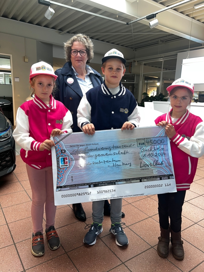 Foto von drei Kindern und einer Frau. Die Kinder halten einen großen Scheck über 45000 Euro für das Kinderkrebszentrum Hamburg in den Händen.